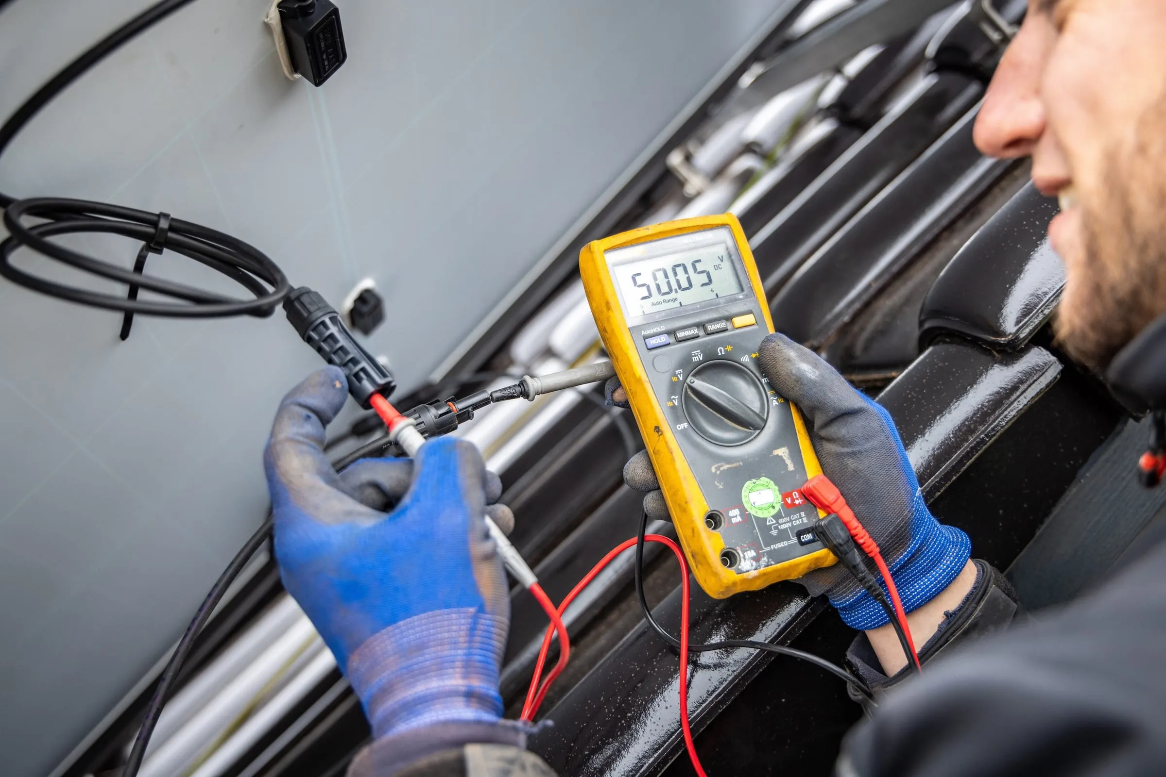 Monteur meet met een multimeter de spanning op een kabel van zonnepanelen