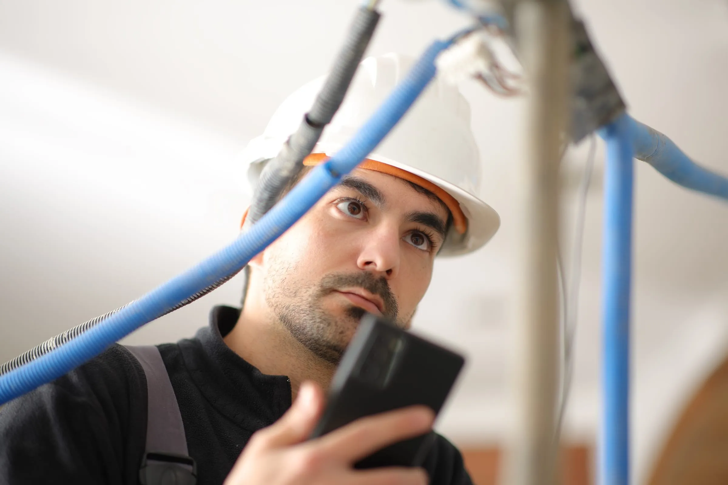 Monteur met helm overlegt aan de telefoon bij een installatie